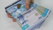Мужчина держит в руке пучку денег по 10 тысяч тенге
